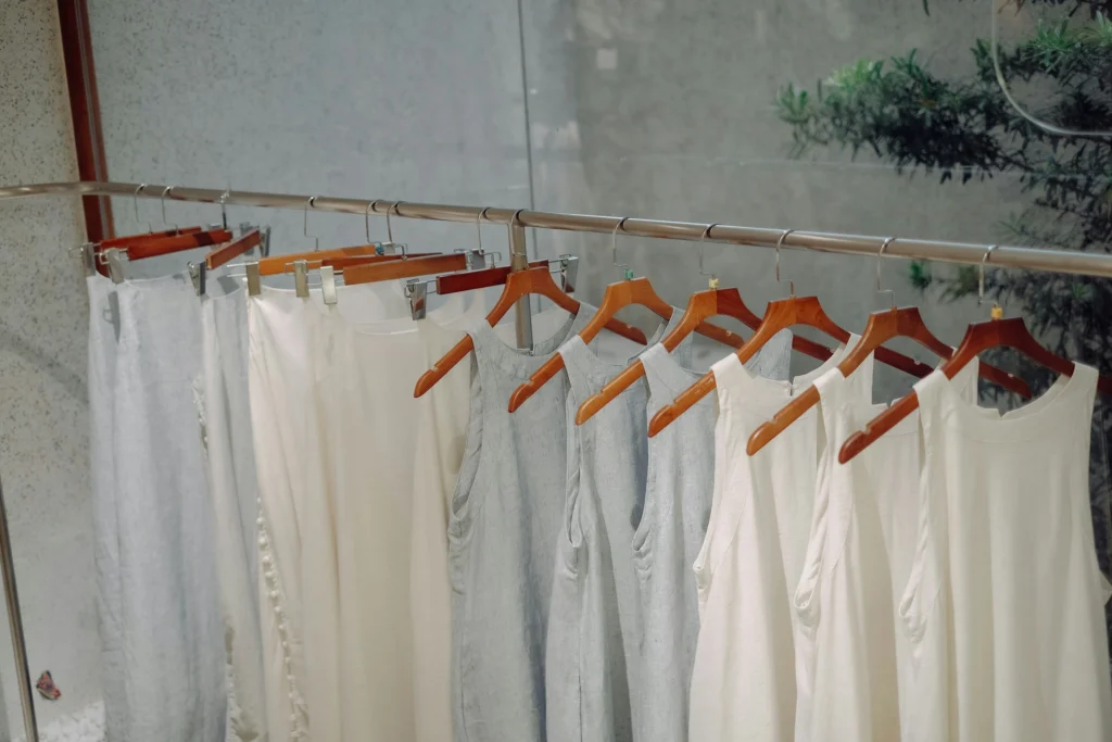 pants and tank tops all white in color, on wooden hangers.