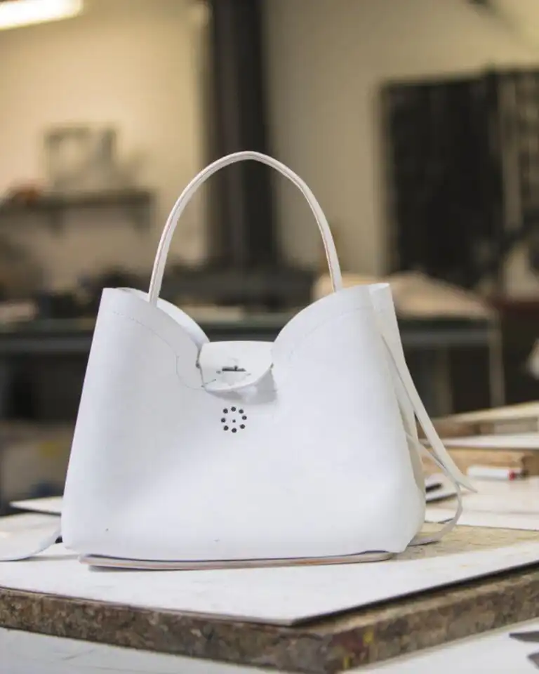 Bag manufacturer in Italy: a white leather handbag on the workbench of an Italian workshop