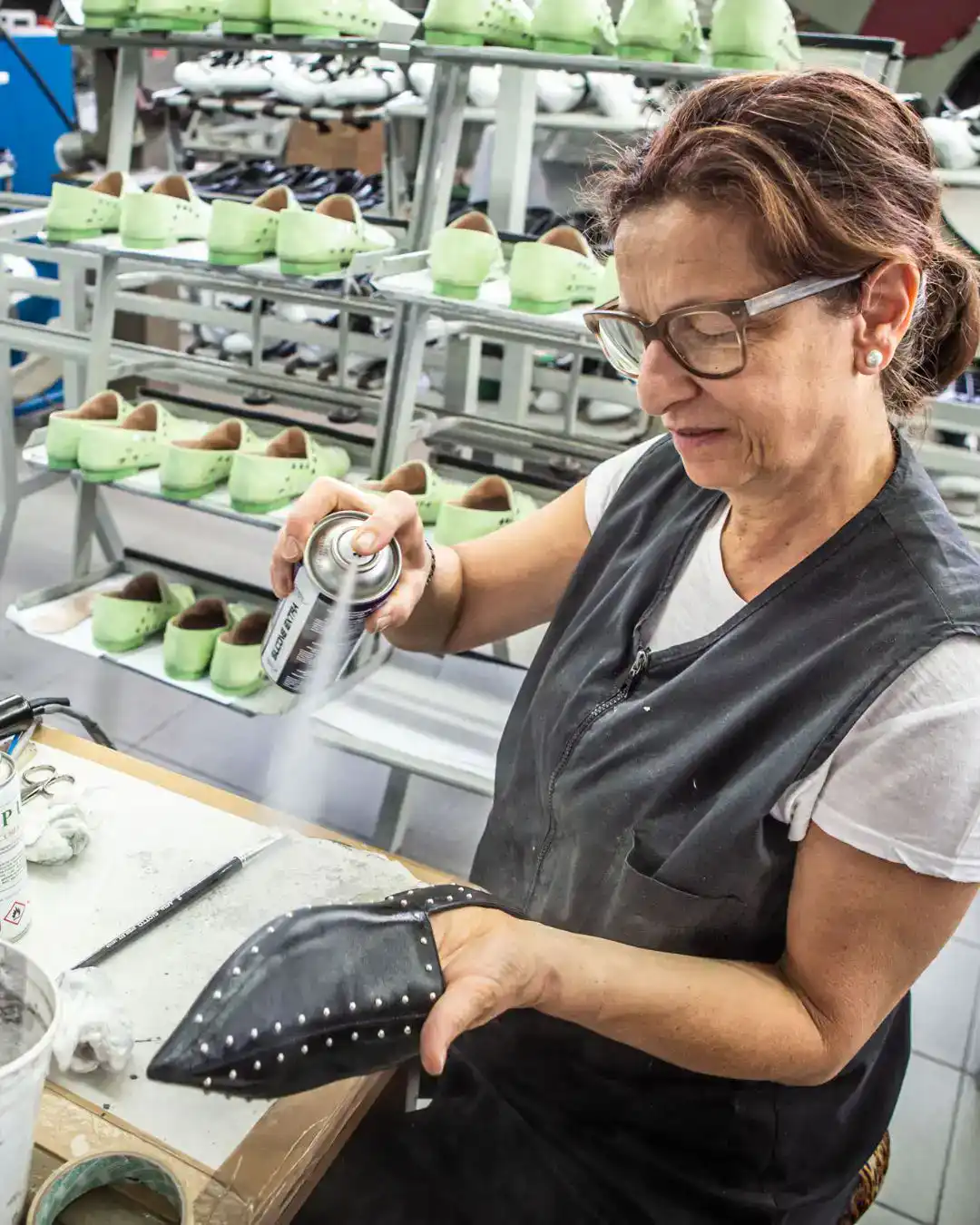 Italian shoe manufacturers at work: an artisan finishes a black leather pump by hand in an Italian footwear workshop