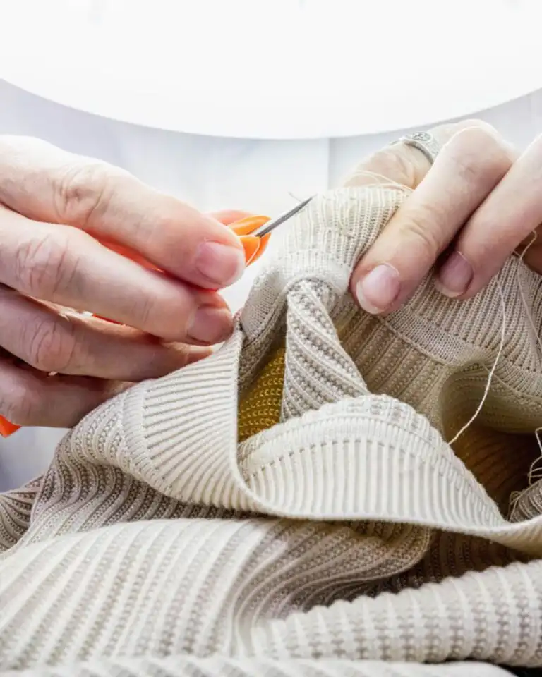 An artisan hand-finishing a knit sweater in an Italian workshop