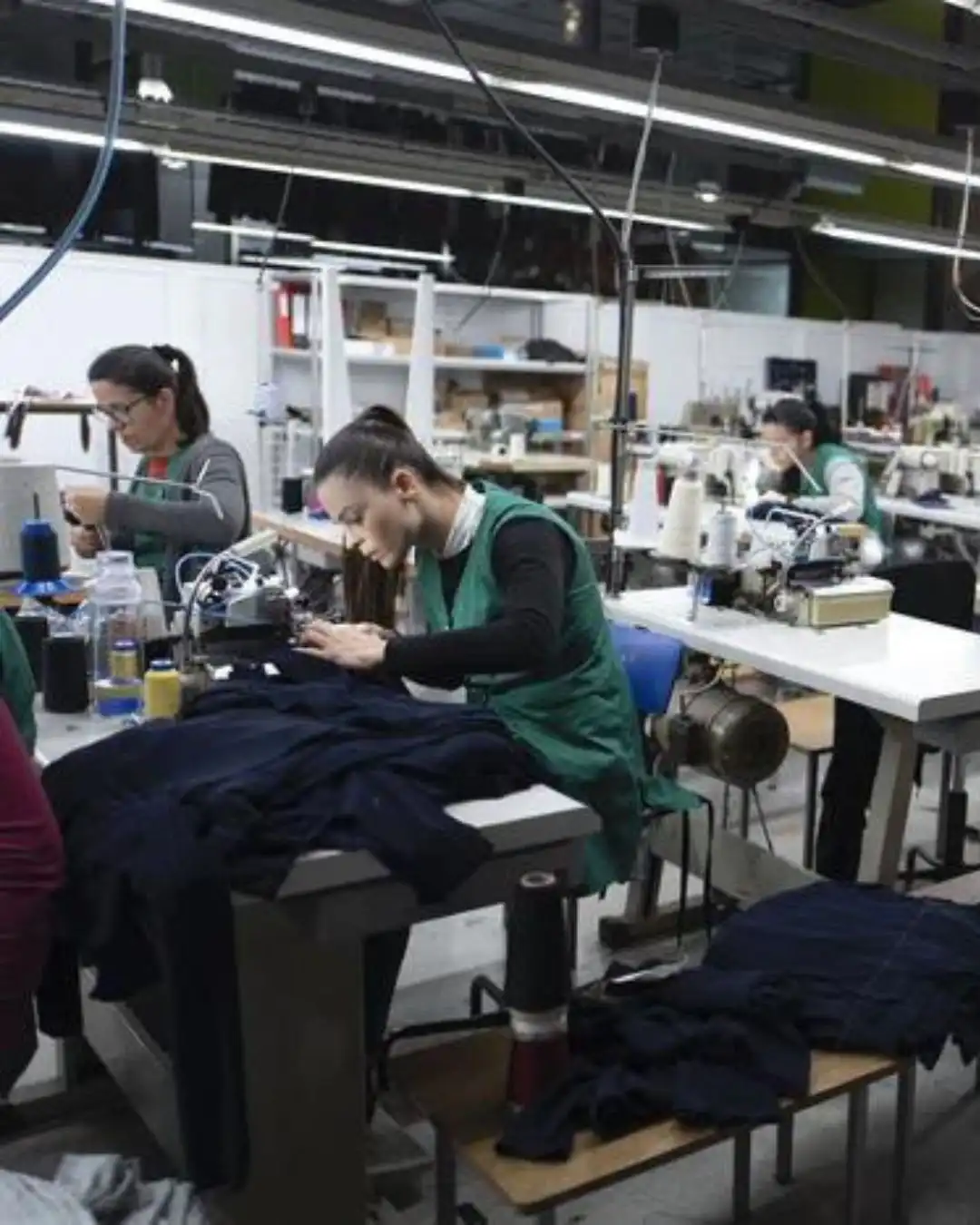 Seamstresses assembling navy knitwear in an Italian workshop