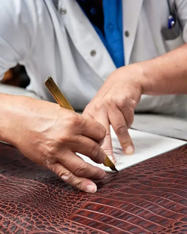 An artisan marking croc-print leather for small leather goods in Italy
