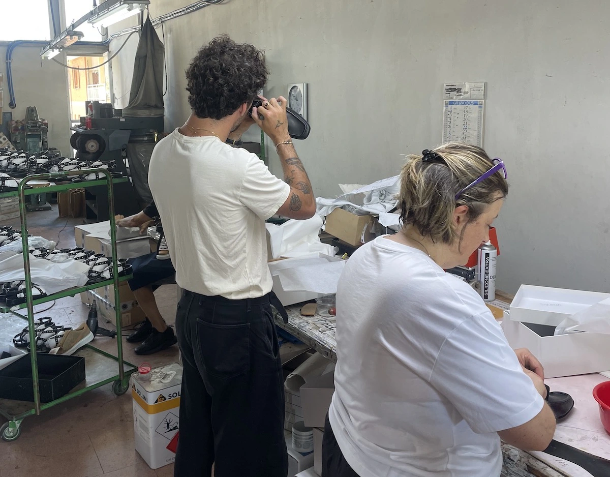 Hands inspecting a garment sample on a workshop table while vetting a clothing manufacturer.