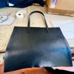 A cut panel of black matte Nebraska leather on the workshop table
