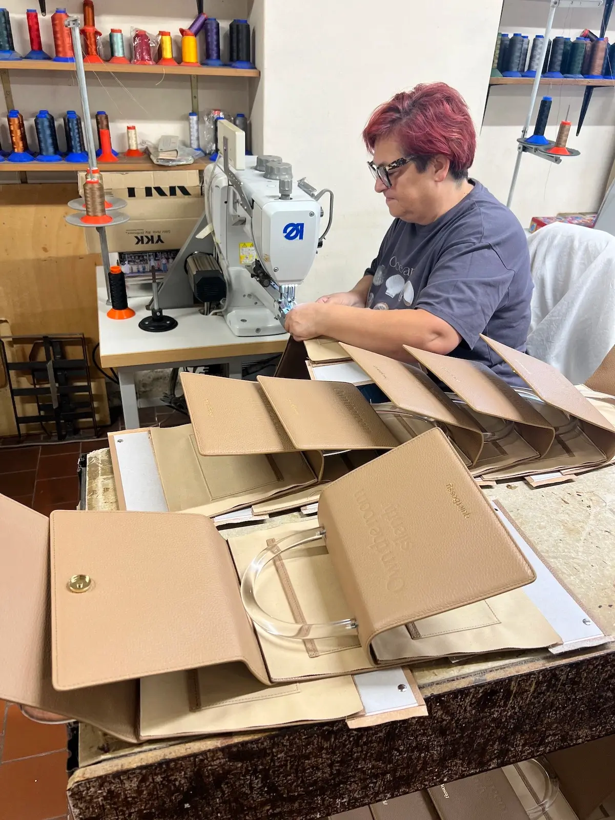 An artisan sewing Maison Veni components at an industrial machine in the workshop