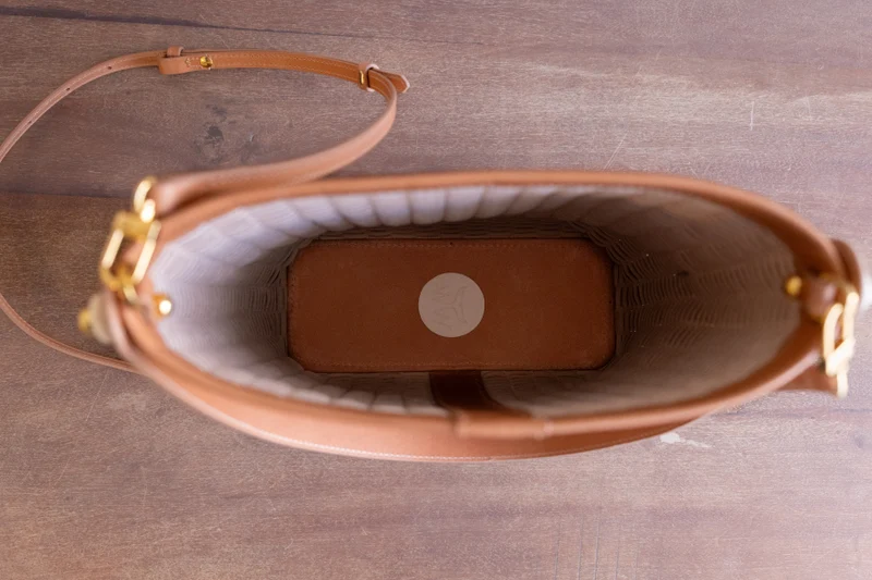 Top-down view inside the woven bucket bag, showing the lined interior and the leather strap