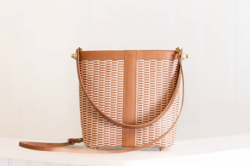 Woven leather bucket bag on a white surface, showing the hazelnut and cream weave