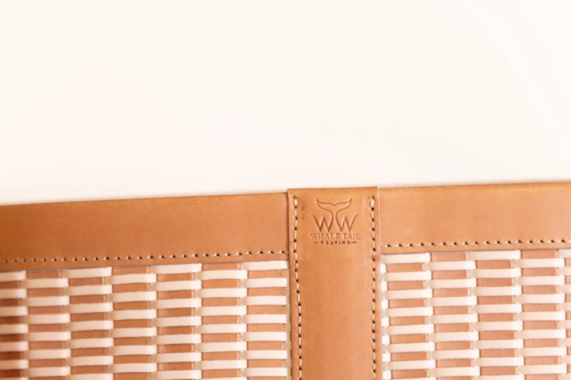 Close-up of the Whale Tail Weaving embossed leather tab on the woven bucket bag