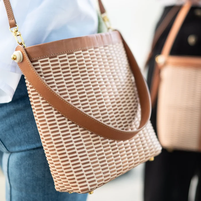 Close-up of the woven leather bucket bag worn crossbody, showing the hand-woven lightship pattern