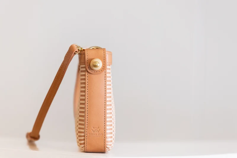Side view of the woven leather clutch showing the gusset and the fossil mammoth knob