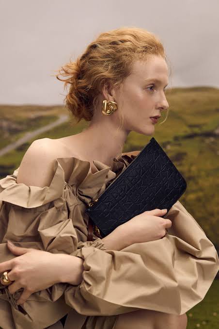 Maison Veni campaign: a model holds the Sarah embossed clutch against a ruffled top
