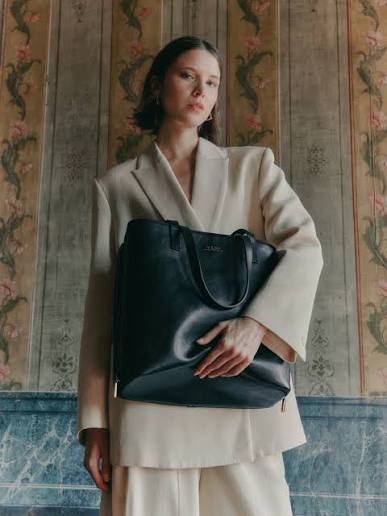 Maison Veni campaign: a model in a cream suit carries the Rebekah tote