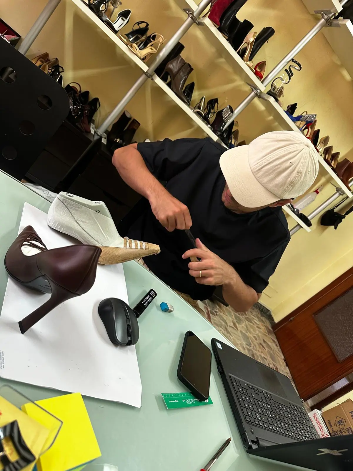 An artisan fits a sculpted heel to a brown pump at the atelier bench