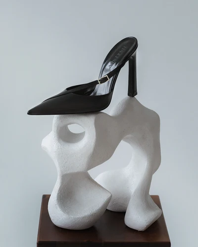 Hagelstam Act One black pointed pump with ankle strap displayed on a white sculpture