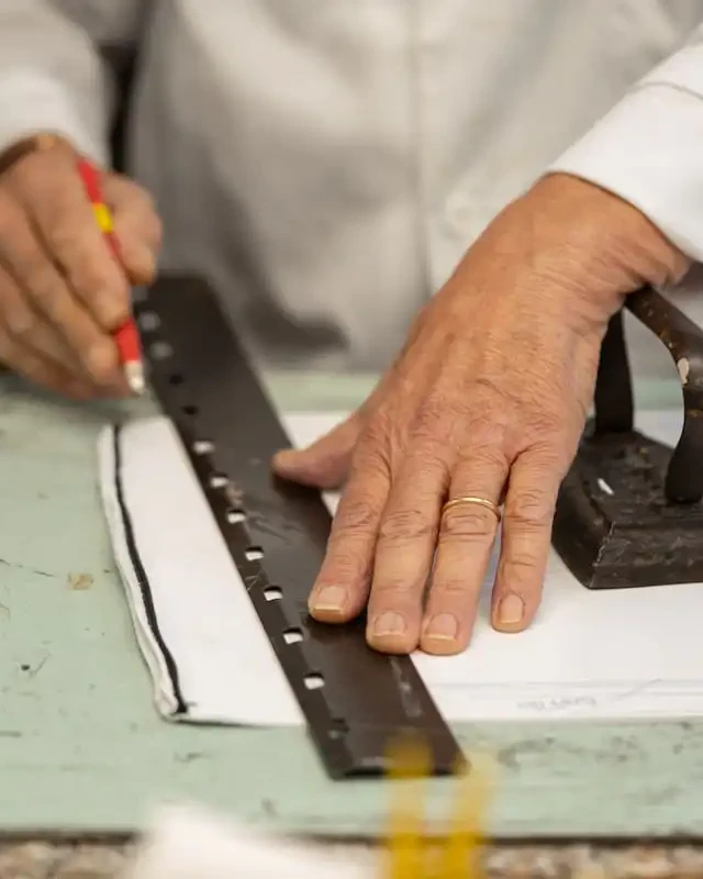 An artisan ruling a pattern on the cutting board of an Italian workshop