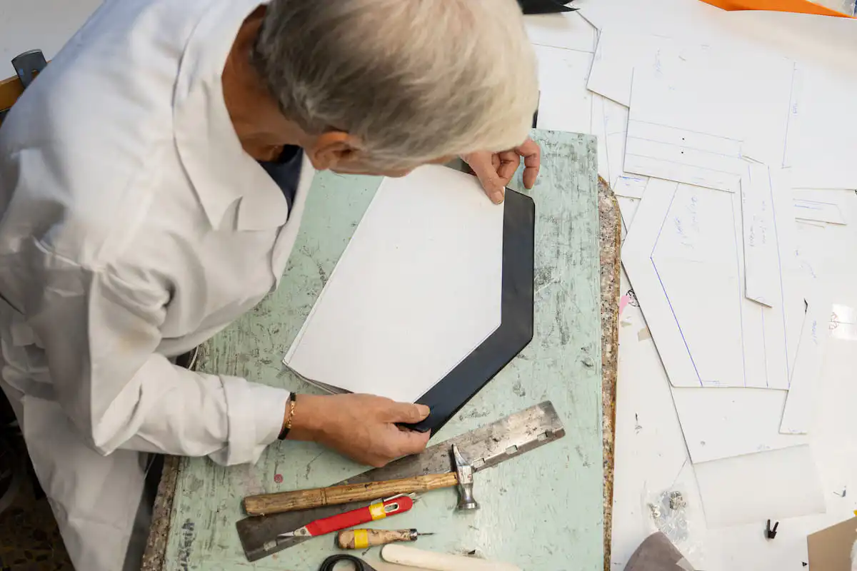 A pattern maker positioning a leather piece on the cutting board in an Italian workshop