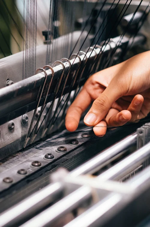 Hands on the needles of a knitting machine in an Italian workshop
