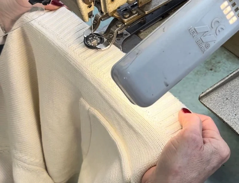 A cream rib sweater on a linking machine in an Italian knitwear workshop